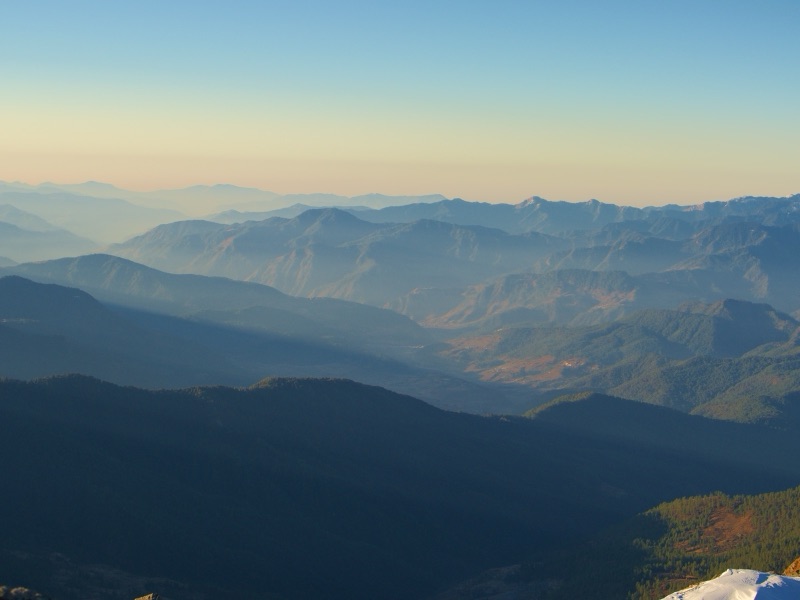 Layered mountain ridges receding into mist at golden hour