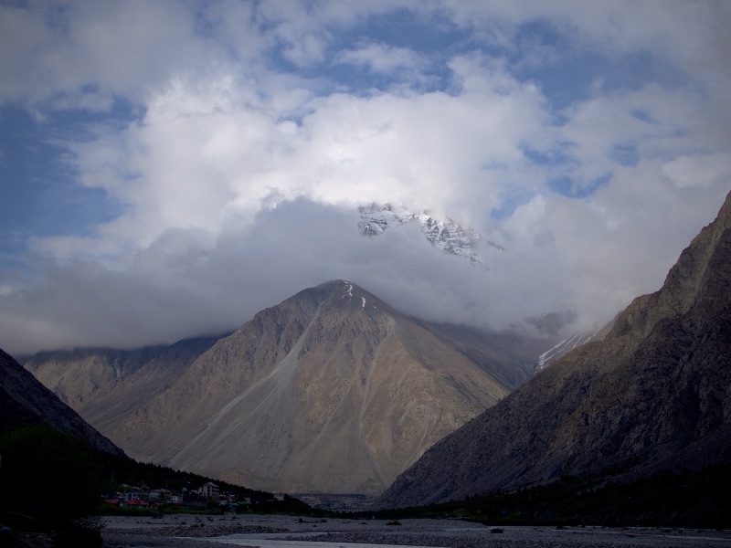 Small village at the base of a massive cloud-shrouded mountain peak