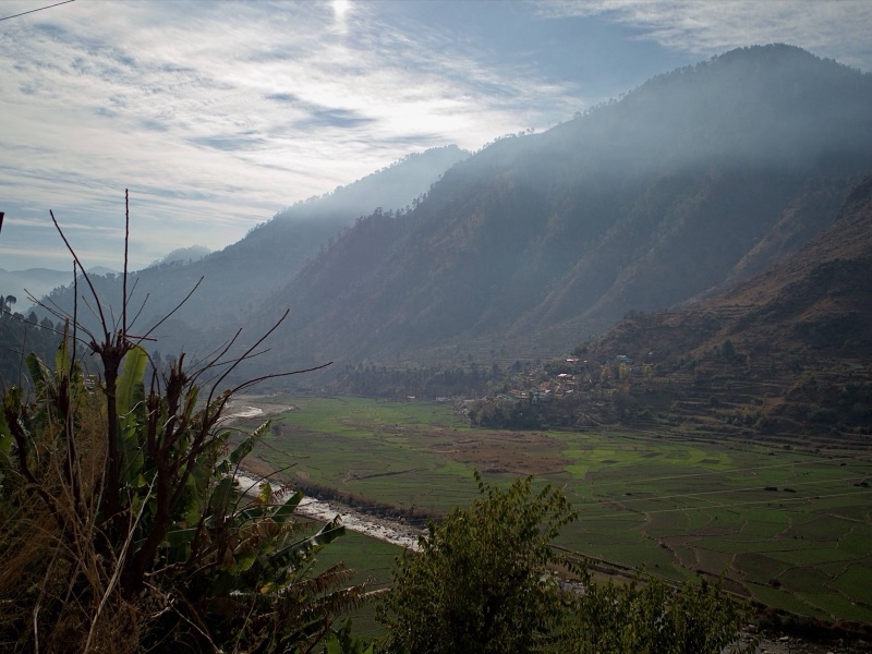 Misty valley with terraced fields and a village lit by morning sun