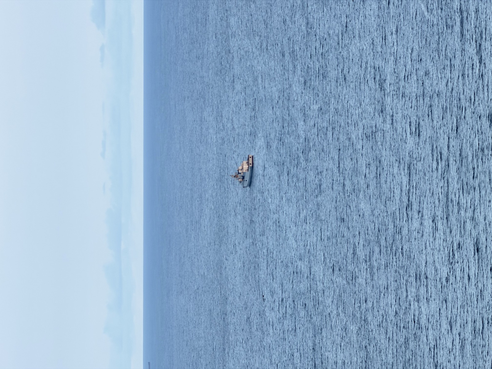 A lone ship on a vast deep-blue ocean