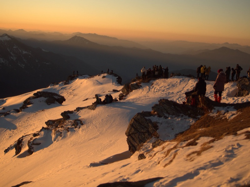 Group of trekkers at a mountain summit during golden hour