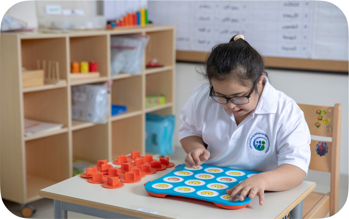 Child wearing glasses with school logo shirt, using interactive learning materials
